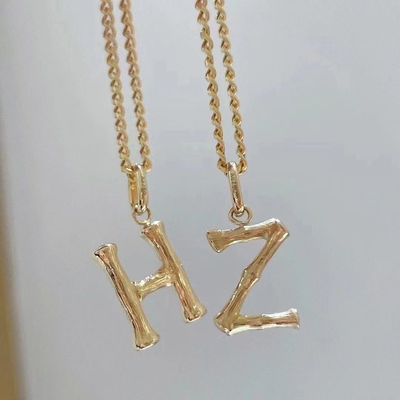 May include: Two gold necklaces with initial pendants. The pendants are in the shape of the letters H and Z. The letters are made to look like branches of a tree.