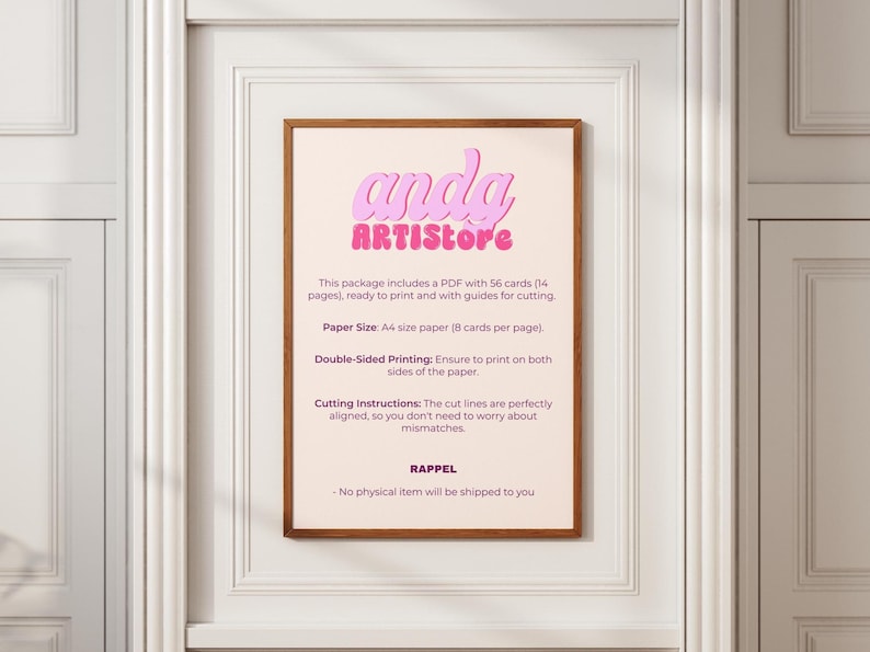 May include: A framed print with the text "anda ARTISstore" in pink bubble letters. The print includes instructions for printing cards, specifying A4 paper size and double-sided printing. The frame is brown, and the background is a light pink.