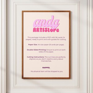 May include: A framed print with the text "anda ARTISTore" in pink and purple. The print provides instructions for printing cards, including paper size, double-sided printing, and cutting instructions. The frame is brown, and the background is a light beige.