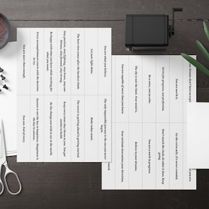 Puede incluir: Un conjunto de tarjetas de motivaci&oacute;n con afirmaciones positivas impresas en ellas. Las tarjetas son blancas con texto negro y est&aacute;n dispuestas en una cuadr&iacute;cula. Las tarjetas est&aacute;n sobre una superficie de madera.