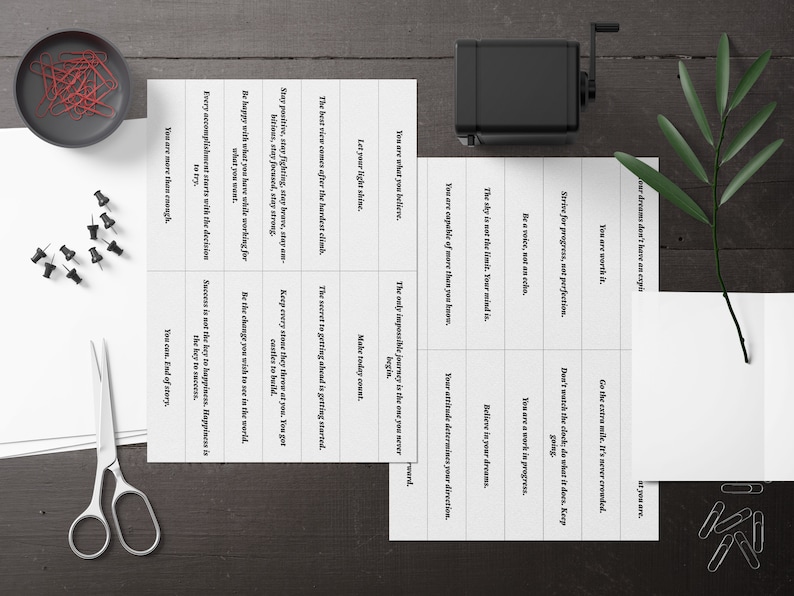 Puede incluir: Un conjunto de tarjetas de motivaci&oacute;n con afirmaciones positivas impresas en ellas. Las tarjetas son blancas con texto negro y est&aacute;n dispuestas en una cuadr&iacute;cula. Las tarjetas est&aacute;n sobre una superficie de madera.
