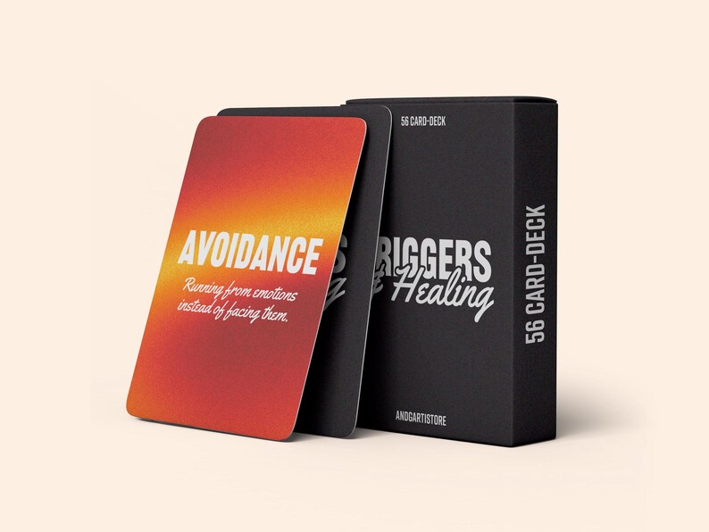 K&ouml;nnte beinhalten: Eine schwarze Box mit dem Text "56 Card Deck" und "Triggers & Healing" auf der Vorderseite. Die Box enth&auml;lt ein Kartenspiel mit einem roten, orangefarbenen und gelben Farbverlaufshintergrund und dem Text "Avoidance" und "Running from emotions instead of facing them".
