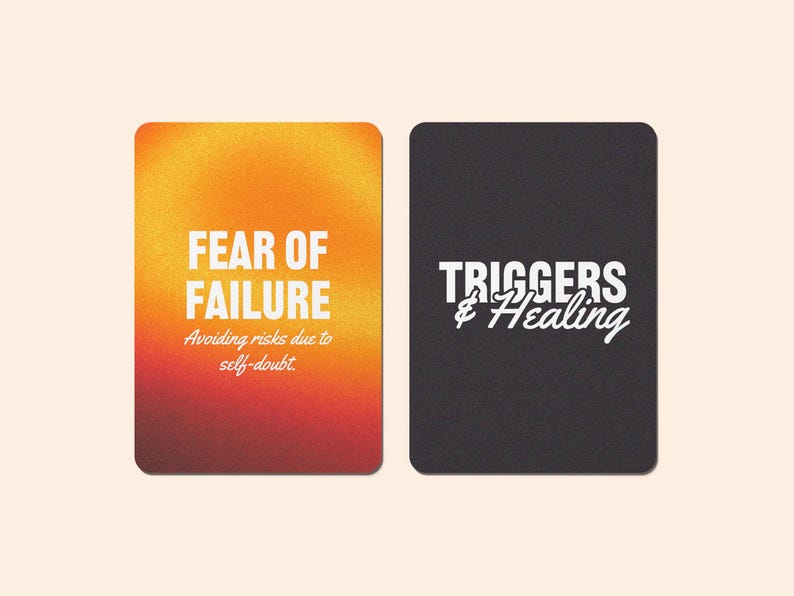 K&ouml;nnte beinhalten: Zwei Karten mit Text darauf. Die erste Karte hat einen Farbverlaufshintergrund in Orange, Gelb und Rot. Der Text auf der Karte lautet "FEAR OF FAILURE" und "Avoiding risks due to self-doubt". Die zweite Karte ist schwarz mit wei&szlig;em Text, der "TRIGGERS & Healing" lautet.