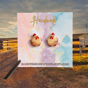 May include: Handmade chicken earrings on a white card with a watercolor background. The card has the text "Handmade" and "NAMIVIBECREATIONS.ETSY.COM".