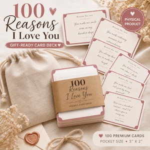 May include: A deck of 100 cards titled 100 Reasons I Love You with a brown paper band, a beige drawstring pouch, and individual cards featuring printed text and pink borders. The cards measure 3 inches by 2 inches as indicated on the packaging.
