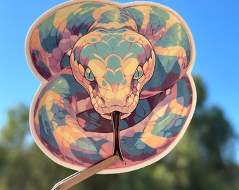May include: A sticker of a colorful snake with a yellow, green, and blue pattern. The snake is coiled up with its head facing forward and its tongue sticking out. The sticker is on a white background.