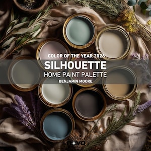 May include: An overhead shot of seven open paint cans arranged in a circle, each filled with a different shade of paint. The cans are gold-rimmed and sit on a neutral-toned fabric, surrounded by greenery. Text on the image reads "COLOR OF THE YEAR 2026 SILHOUETTE HOME PAINT PALETTE BENJAMIN MOORE."