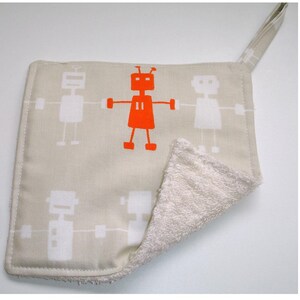 May include: A beige kitchen pot holder with a white robot design and an orange robot in the center. The pot holder has a white terry cloth backing and a loop for hanging.