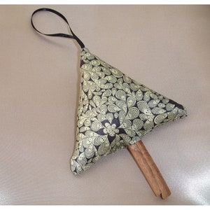 May include: A handmade, triangular ornament with a black ribbon loop. The ornament features a cream-coloured fabric with a black paisley pattern. A wooden stick is attached to the bottom.