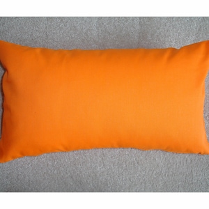 May include: A solid orange rectangular cushion. The cushion is made of a soft, smooth fabric.