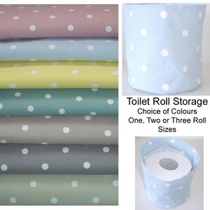 May include: A collection of fabric toilet roll storage containers featuring a white polka dot pattern on various solid colors including pink, blue, yellow, teal, gray, and green. The text reads Toilet Roll Storage Choice of Colours One, Two or Three Roll Sizes.