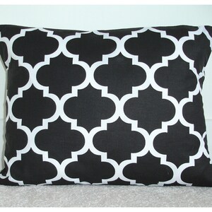May include: Black and white geometric throw pillow with a quatrefoil pattern. The pillow is made of a soft, durable fabric and is perfect for adding a touch of modern style to any room.