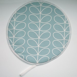 May include: A round, blue and white pot holder with a white trim and a white string handle. The pot holder has a repeating pattern of stylised white leaves on a light blue background.