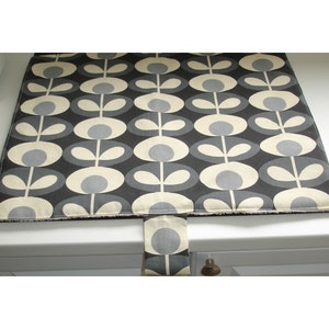 May include: A black and white kitchen counter mat with a repeating pattern of stylised grey flowers. The mat has a grey fabric loop handle.