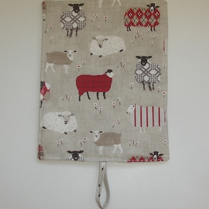 May include: A beige linen fabric tote bag with a red and white checked pattern and a black and white sheep design. The bag has a loop handle.