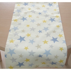 May include: A white table runner with a repeating pattern of blue, yellow and grey stars.
