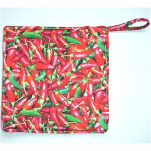 May include: Red and green chili pepper hot pad with a hanging loop. The hot pad is made of fabric with a chili pepper print.