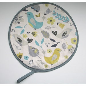 May include: Round, grey-trimmed, white fabric hot pad with a repeating pattern of colourful birds, flowers, and leaves.