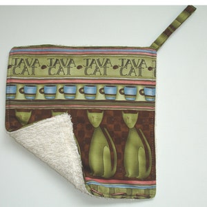 May include: A green and brown pot holder with a cat and coffee cup design. The text "Java Cat" is repeated across the top of the pot holder. The pot holder has a white terry cloth backing.