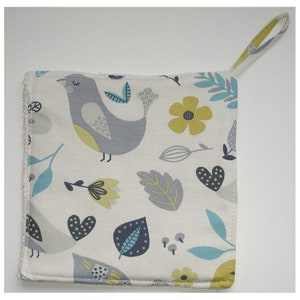 May include: A white cotton pot holder with a grey and yellow bird, green leaves, and yellow flowers pattern. The pot holder has a loop handle.