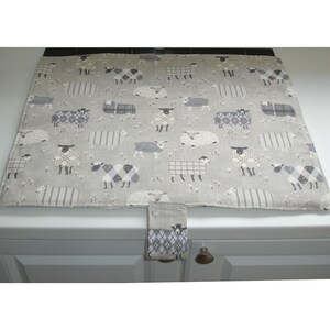May include: A grey and white kitchen counter protector with a sheep pattern. The protector has a flap that can be tucked under the counter.