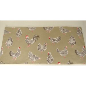 May include: A beige fabric table runner with a repeating pattern of white and grey chickens. The chickens have red combs and wattles.