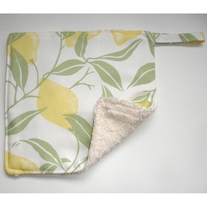 May include: A white kitchen towel with a lemon print on one side and a soft, white terry cloth on the other side. The towel has a loop for hanging.