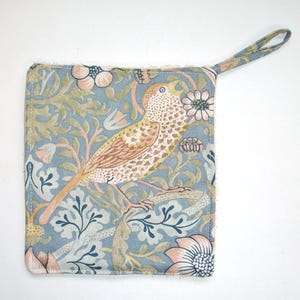 May include: A blue and green patterned pot holder with a bird design. The pot holder has a loop handle.