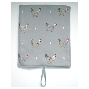 May include: A grey kitchen pot holder with a white and grey chicken pattern and white dots. The pot holder has a loop handle.