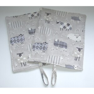 May include: Two grey and white kitchen tea towels with a sheep pattern. The towels have a loop handle.