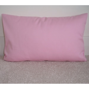 May include: A plain pink pillow with a smooth, soft fabric surface.