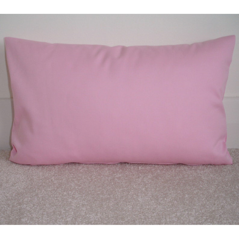 May include: A plain pink pillow with a smooth, soft fabric surface.