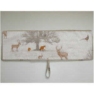 May include: A beige fabric valance featuring a woodland scene with deer, a fox, a squirrel, and a pheasant. The valance has a loop on the back for hanging.
