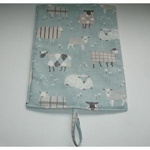 May include: A light blue fabric pouch with a loop handle. The pouch is decorated with a repeating pattern of white, black and grey sheep on a light blue background.