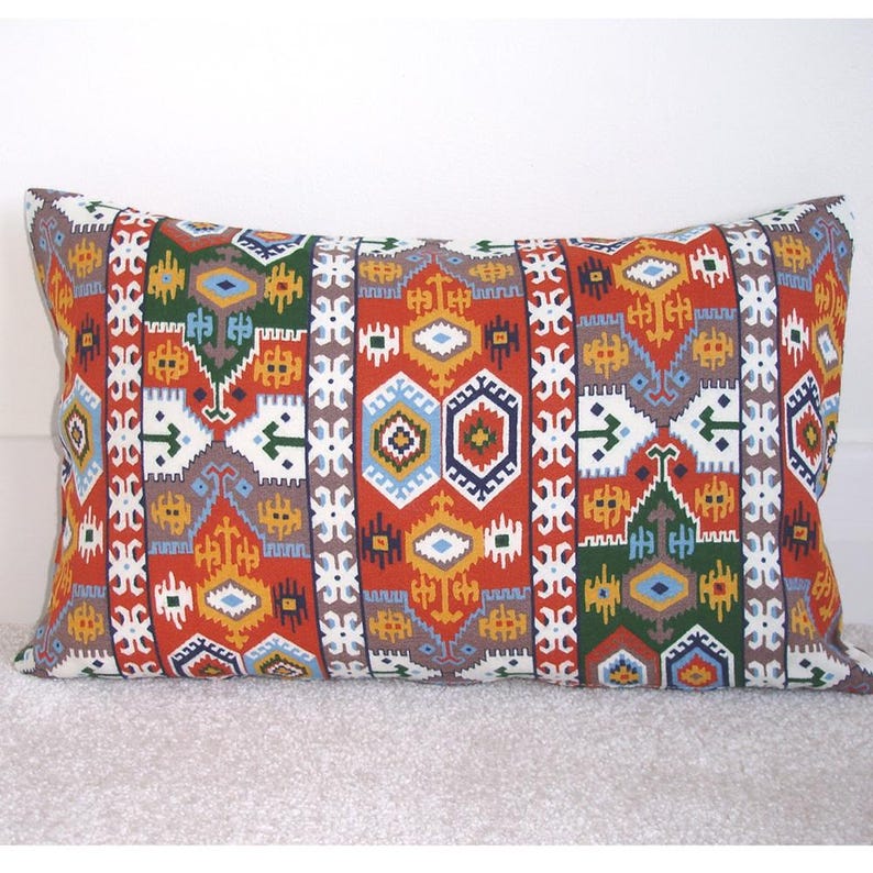 May include: A rectangular pillow with a colorful geometric pattern in shades of red, orange, yellow, green, blue, and white. The pattern is reminiscent of traditional Turkish or Moroccan textiles.
