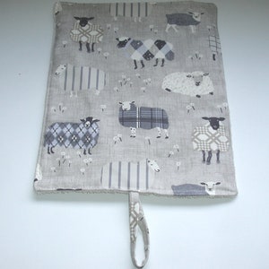 May include: A grey and white fabric pot holder with a loop handle. The pot holder features a repeating pattern of black and white sheep with different patterns on their wool.