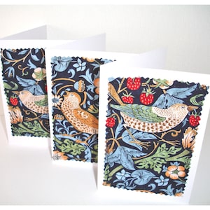 May include: Three blank greeting cards with a colorful fabric design featuring birds and flowers. The fabric is a dark blue background with green, red, and brown accents.