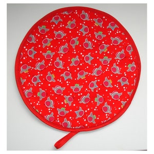 Peut inclure: Un dessous de plat rond rouge avec une boucle de suspension. Il présente un motif répété d'oiseaux gris et rouges avec des points blancs sur un fond rouge. Le bord est bordé d'une bordure rouge. Diamètre d'environ 20 cm.