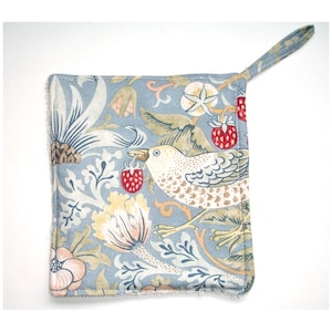 May include: A blue and white cotton pot holder with a floral pattern and a bird with a strawberry in its beak. The pot holder has a loop handle.