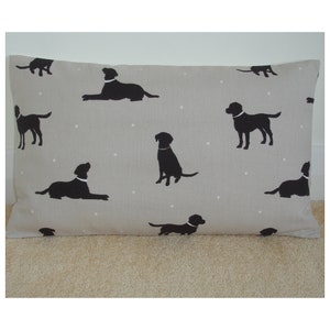 May include: A gray pillow with a white polka dot pattern and black silhouettes of Labrador Retrievers. The pillow is made of a soft, linen-like fabric.