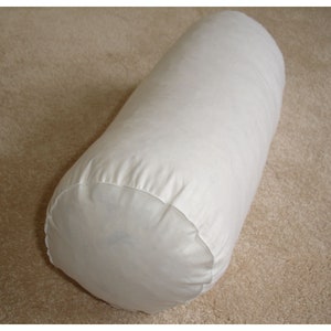 May include: A white cylindrical bolster pillow. The pillow is made of a soft, light-coloured fabric and has a rounded shape. It is designed for comfort and support.
