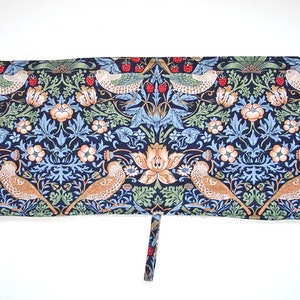 May include: A blue and green fabric pot holder with a floral pattern and birds. The pot holder has a loop on the top for hanging.