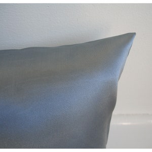 May include: A light blue satin pillowcase. The pillowcase is smooth and has a subtle sheen.