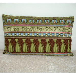 May include: A green and brown rectangular cushion with a repeating pattern of cats and coffee cups. The pattern includes the words "JAVA" and "CAT" in a brown font.
