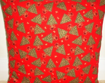 May include: Red square pillow with a repeating pattern of green and gold Christmas trees, bows, and small white stars. The trees have a dotted texture and are decorated with gold bows. The pillow is a festive holiday decoration.