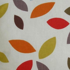 May include: A white fabric featuring a repeating pattern of scattered, almond-shaped leaves in various colors including orange, lime green, dark brown, and red. The leaves are oriented in different directions across the surface of the textile.