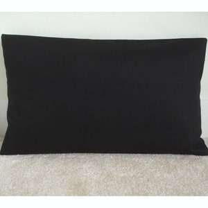 May include: A plain black pillow with a rectangular shape. The pillow is made of a soft, smooth fabric.