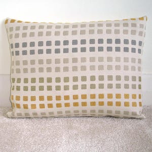 May include: A rectangular throw pillow with a geometric pattern of squares in shades of beige, gray, green, and yellow.