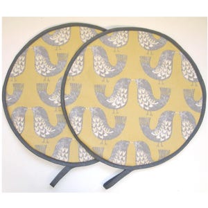 May include: Two round yellow pot holders with a grey bird pattern and a grey trim. Each pot holder has a grey loop handle.