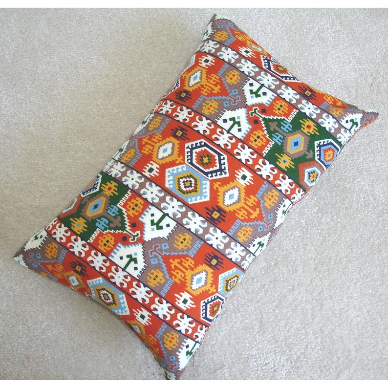 May include: A rectangular pillow with a colorful geometric pattern in shades of orange, red, blue, green, and white. The pattern is reminiscent of traditional Turkish or Moroccan textiles.